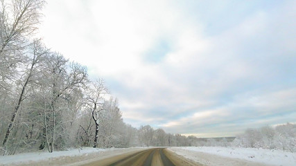 Country road in winter along the forest with white snow trees