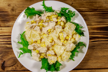 Festive salad with chicken breast, sweet corn, canned pineapple and mayonnaise on wooden table