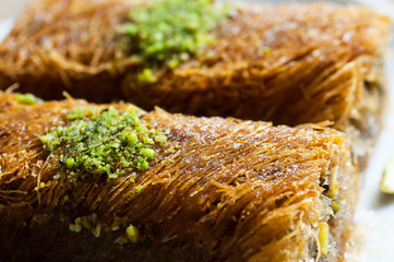 Turkish famous dessert burma kadayif on plate with pistachio nuts, Shredded dough baked in syrup...