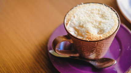 Mug of brown cacao decorated with nut crumb on a wooden table.