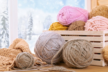 Woolen yarn and fabric on the window sill. Beautiful view outside the window - winter scenery and snow.