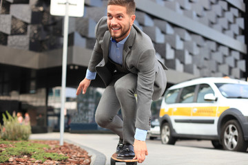 Confident young businessman in business suit on longboard hurrying to his office, on the street in the city