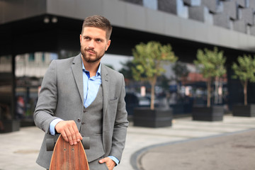 Confident young businessman walking on the street, using longboard. - Powered by Adobe