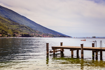 View with wooden dock pier extending over blue lake water and mountains