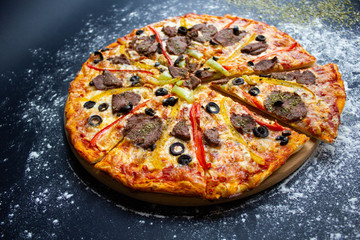 hot tasty delicious rustic homemade american pizza with tomato with thick crust on black table