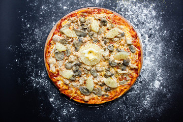 hot tasty delicious rustic homemade american pizza with tomato with thick crust on black table