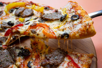 Close up slices of cheese pizza on a spatula