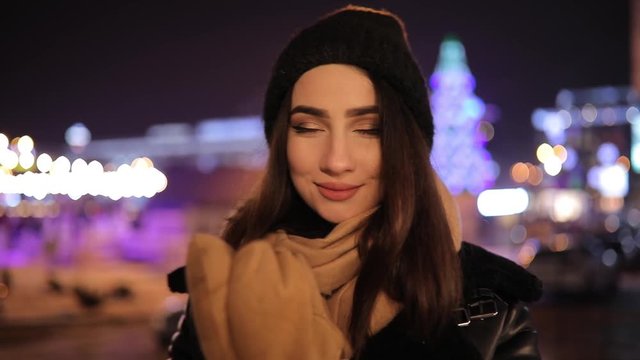 Cute woman portrait in night winter city turn face looking at camera