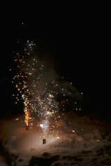 Bright colorful multicolored fireworks fountain in the snow at night