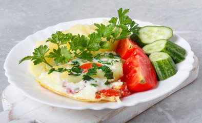 Hot tasty mashed potatoes with scrambled eggs, tomatoes, cucumbers and fresh parsley