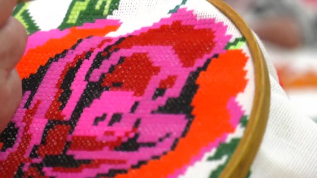 The needlewomen in national costumes embroider on the hoop. Traditional red and black cross-stitch. Belarusian folk embroidery, three colors - white, red and black
