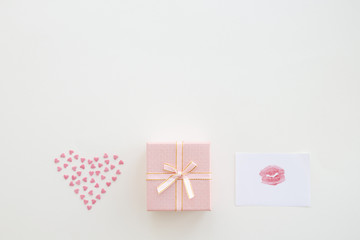 Pink gift box, kiss on paper and heart of small hearts on beige background. Congratulation concept