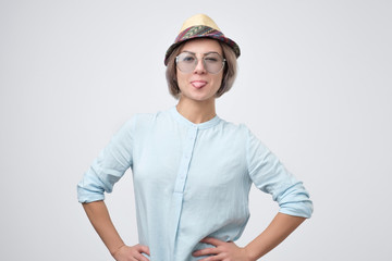 Beautiful young female with pleasant appearance, shows tongue, has fun.