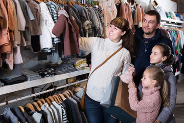 Family with children choosing clothes for new baby
