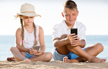 Smiling kids on beach with phone in hands