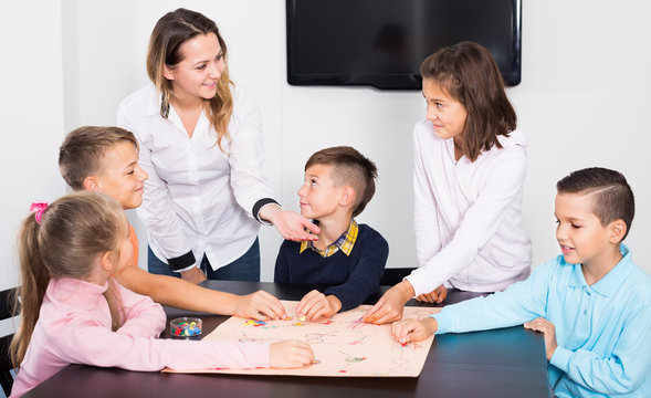 Elementary age smiling children at table with board game and dice
