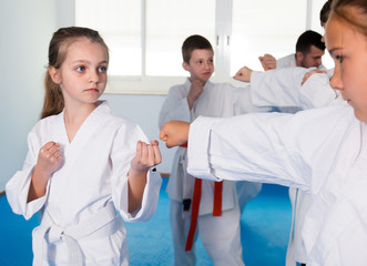 Obraz na płótnie Canvas Happy children sparring in pairs in karate class