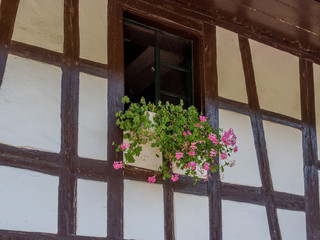 Old window of a farm in rural Switzerland with typical cranesbills flowers