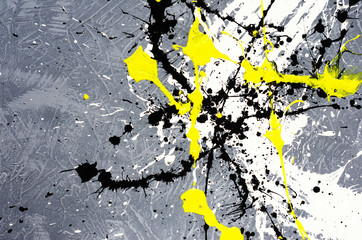 a spot of white and black and yellow spilled paint on a concrete textured surface