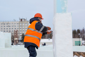 Worker covers the joints of ice panels with wet snow