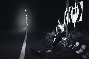  young girl sitting and playing guitar on road side with road sign background, journey of musician concept © yupachingping