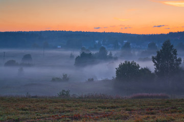 Pink dawn sky and blue mist over Russian fields.