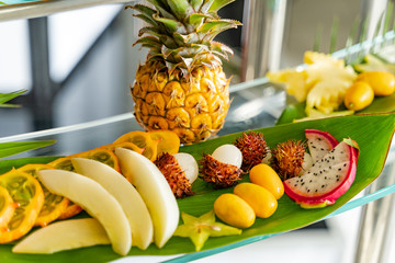 Mixed of many exotic fresh fruits on a glass table for banquet. Group of fresh natural and organic fruits assorted on green leaves.