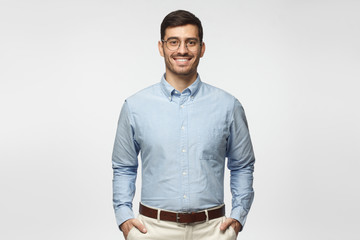 Portrait of young male teacher in blue shirt isolated on gray background