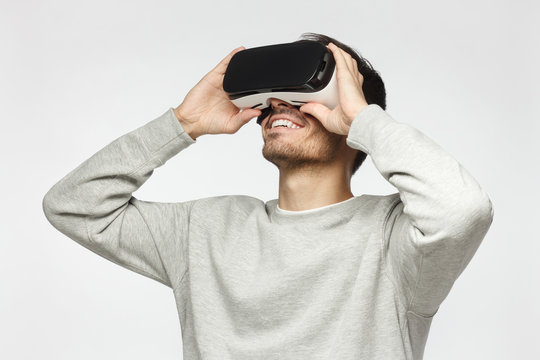 Handsome man playing video games in VR goggles or 3d glasses, wearing virtual reality headset for on his head - Powered by Adobe