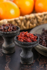 Two black burnt ceramic bowls for hookah Smoking are filled with different types of hookah on the background of ripe oranges and tangerines