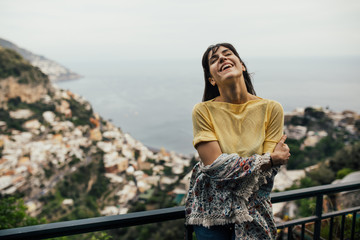 Fototapeta premium Smiling young woman enoying seaview in Positano,Italy. Vacation on Amalfi coast.Happy tourist in Europe.Italian coast beauty, woman enjoying scenic panorama.Experiencing italian lifestyle
