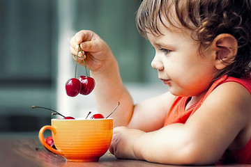 little girl eating a sweet cherry