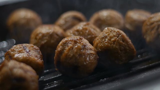 chef fry raw meatballs in iron pan on hot stove for steak dinner meal. Seamless cinemagraph video