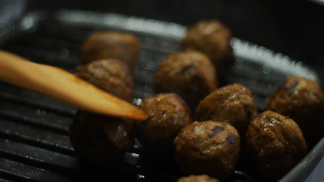 chef fry raw meatballs in iron pan on hot stove for steak dinner meal