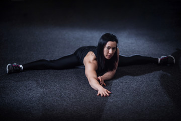 Fototapeta na wymiar athletic woman doing splits in the gym. Woman doing yoga