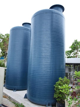 Water Storage Tank: Two Blue Water Storage Tanks Made Of Fiberglass, Mounted On A Concrete Base. For Paying Water To Homes Or Small Businesses