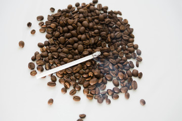 Scattered grains of black coffee with a Smoking cigarette on their background.  Selective focus. Copy space.