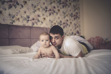 Fototapeta na wymiar fatherhood, Gentle dad and baby son together bed