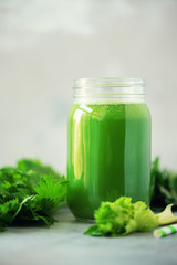 Bottle of green celery smoothie on grey concrete background. Banner with copy space. Square crop. Fresh juice for detox. Vegan, alkaline healthy diet concept