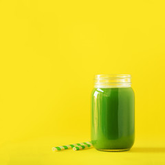 Bottle of green celery smoothie on yellow background. Banner with copy space. Square crop. Fresh juice for detox. Vegan, alkaline healthy diet concept