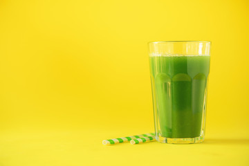 Glass of green celery smoothie on yellow background. Banner with copy space. Fresh juice for detox. Vegan, alkaline healthy diet concept