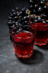 two glasses of red young wine on dark table, vertical