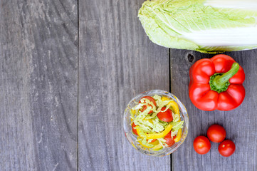 Vegetable salad with fresh vegetables lying separately on a wooden rustic vintage grey background.