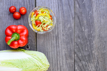 Vegetable salad with fresh vegetables lying separately on a wooden rustic vintage grey background.