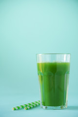 Glass of green celery smoothie on blue background. Banner with copy space. Fresh juice for detox. Vegan, alkaline healthy diet concept