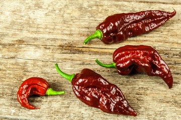 Chili pepper on wooden background.Extra hot chili pepper Naga Bhut Jolokia Chocolate.Raw food. Sale...