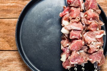 Pieces of raw meat are strung on skewers. Close-up with space for copy. View from above.