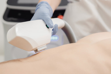 Close-up of device for laser hair removal in process. Master hand. Concept beauty, smoothness to...