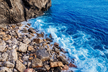 Top view blue ocean water, waves breaking stones. Concept freedom, strength.