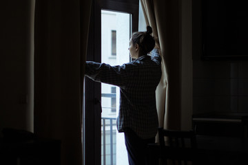 Woman opening curtains and looking through the window